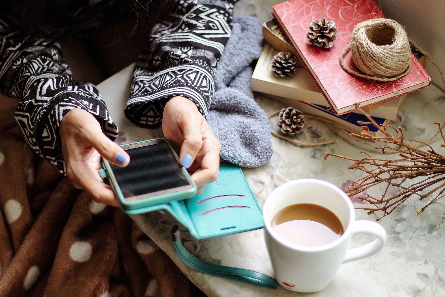 NumeroWunder - Numerologin und Thetahealing Praktikerin - Eine Person hält ein Smartphone neben einem Laptop und einer Tasse Kaffee.